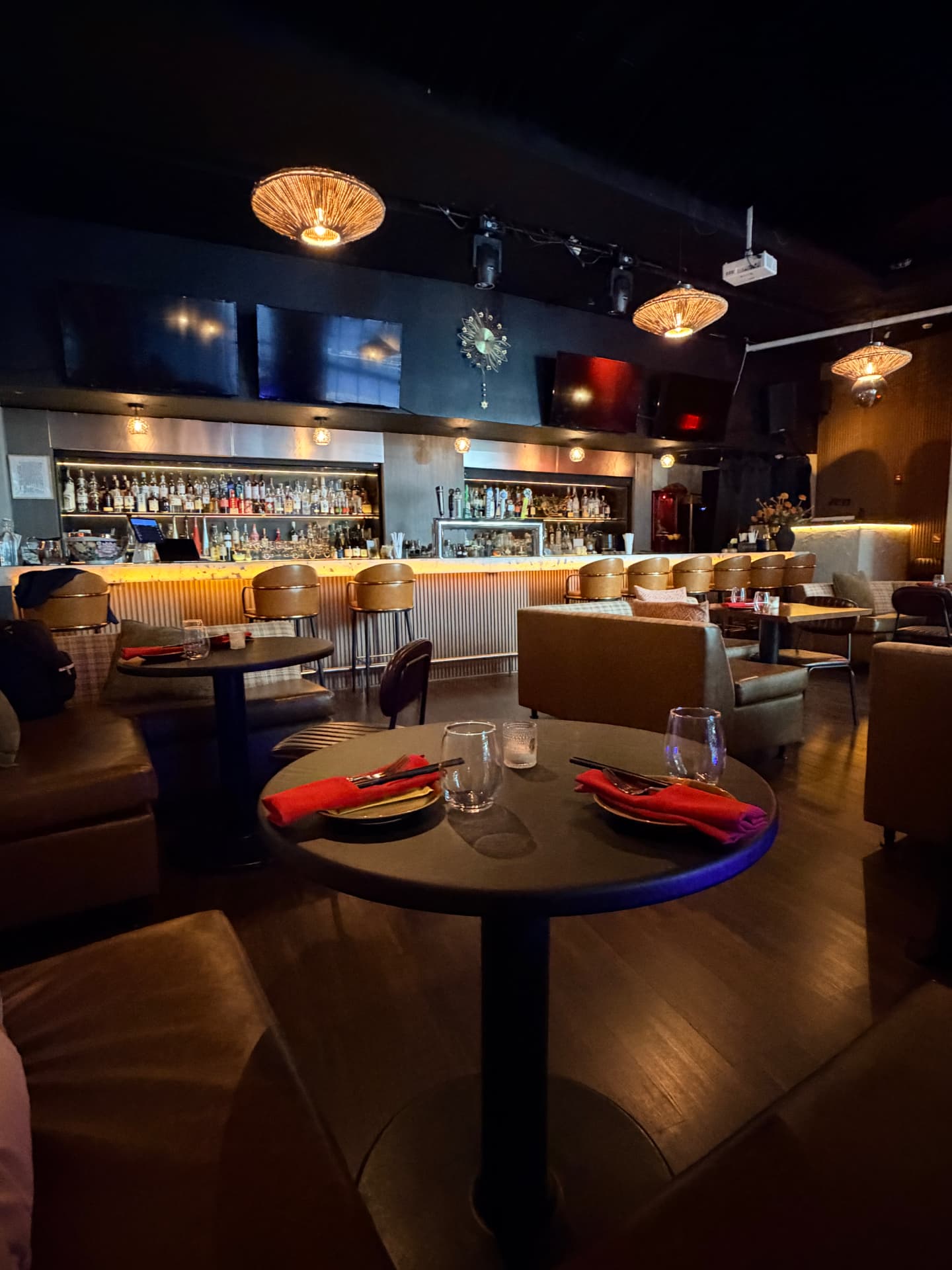 Bar area with gold stools, backlit bottles and woven pendant lights